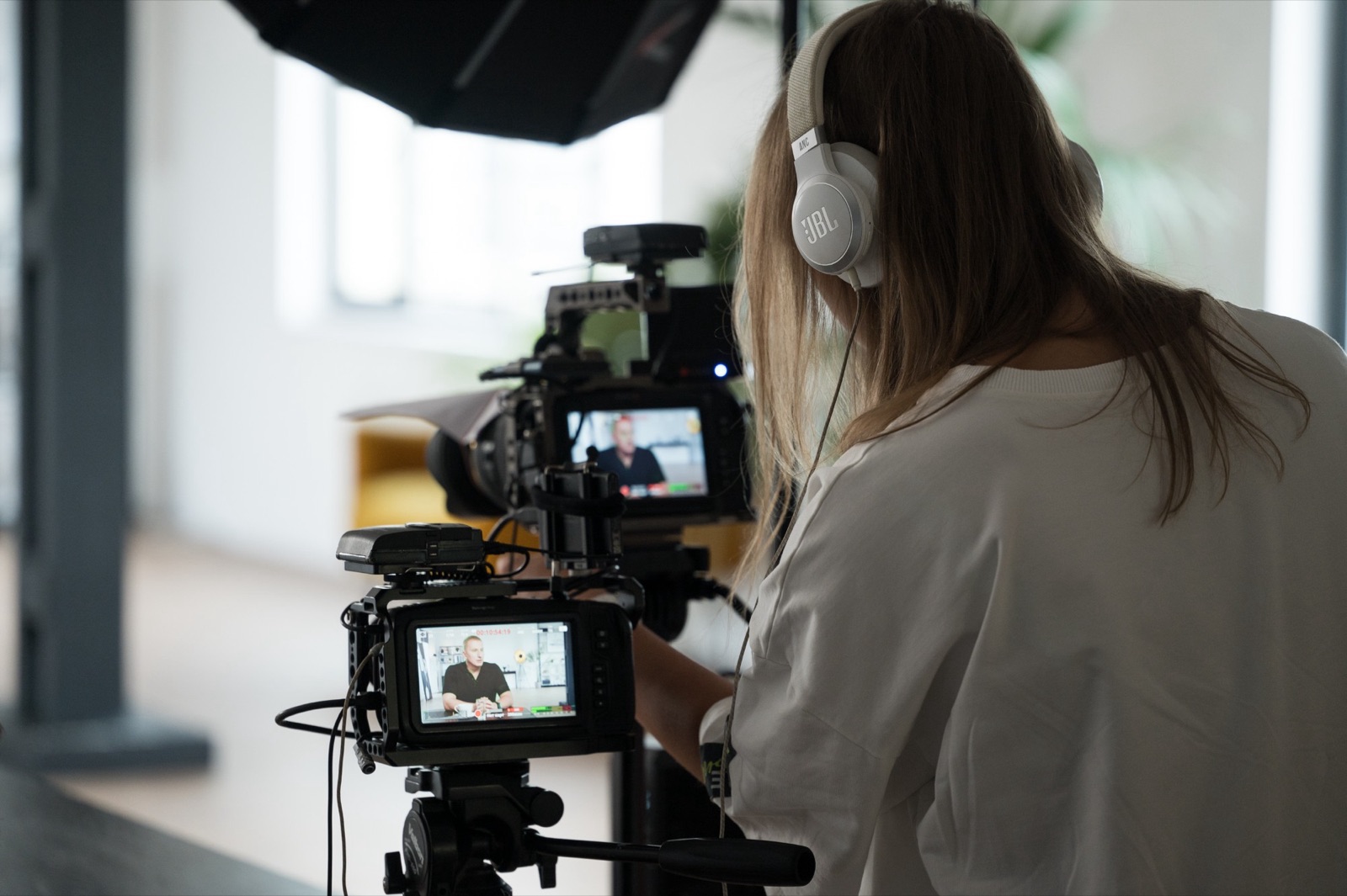 B2B video production: behind two cameras on a corporate interview shoot, the speaker on both monitors