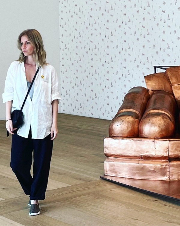 Masha in a gallery next to a giant copper sculpture